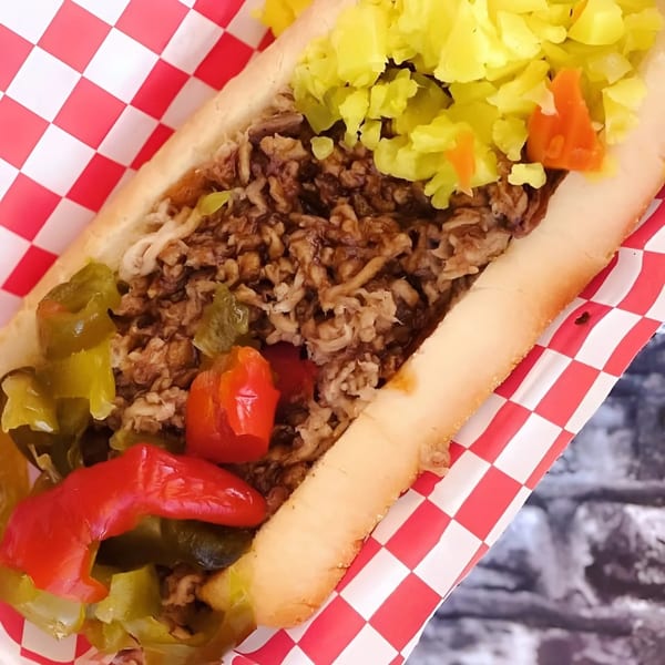 A No Sauce AZ Smokehouse BBQ sandwich with pulled pork, yellow relish, and red and green peppers.