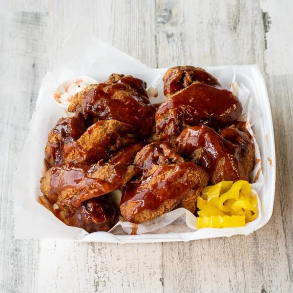 No Sauce AZ Smokehouse BBQ chicken wings with sauce and yellow peppers in a white container.