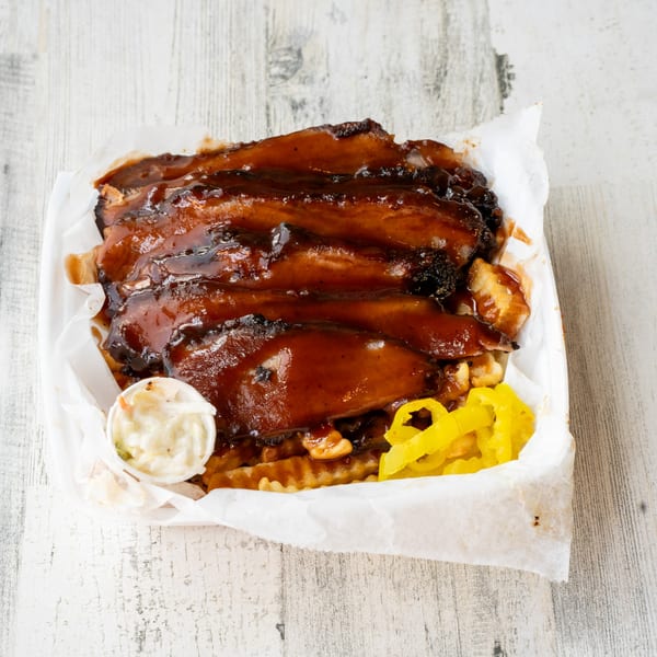 No Sauce AZ Smokehouse BBQ brisket with fries, coleslaw, and yellow peppers in a white container.